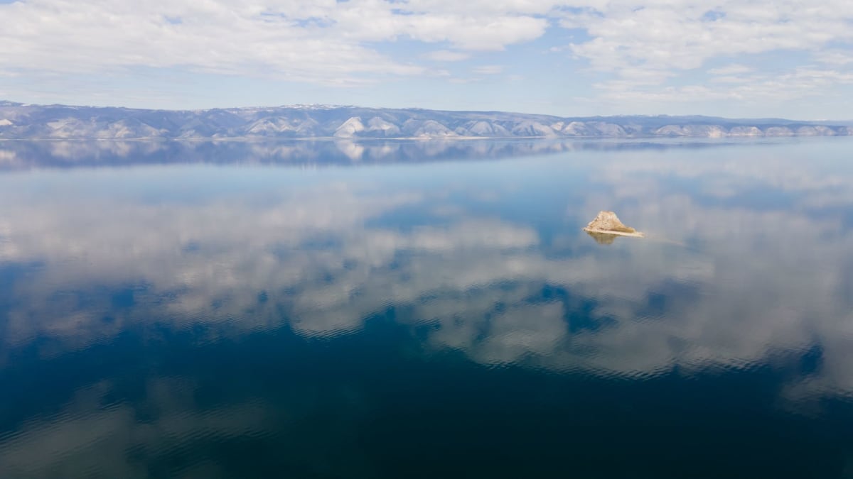 Pescadores en el hielo en el frente de agua de Slyudyanka, perforando agujeros en el lago helado con la estación de mármol visible al fondo