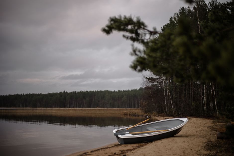 Un bateau de pêche en bois tiré sur la plage de sable volcanique noir de Choshuenco avec le Lago Panguipulli derrière