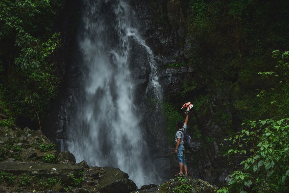 Dos excursionistas de pie en el mirador brumoso frente a las cascadas gemelas de Tad Fane