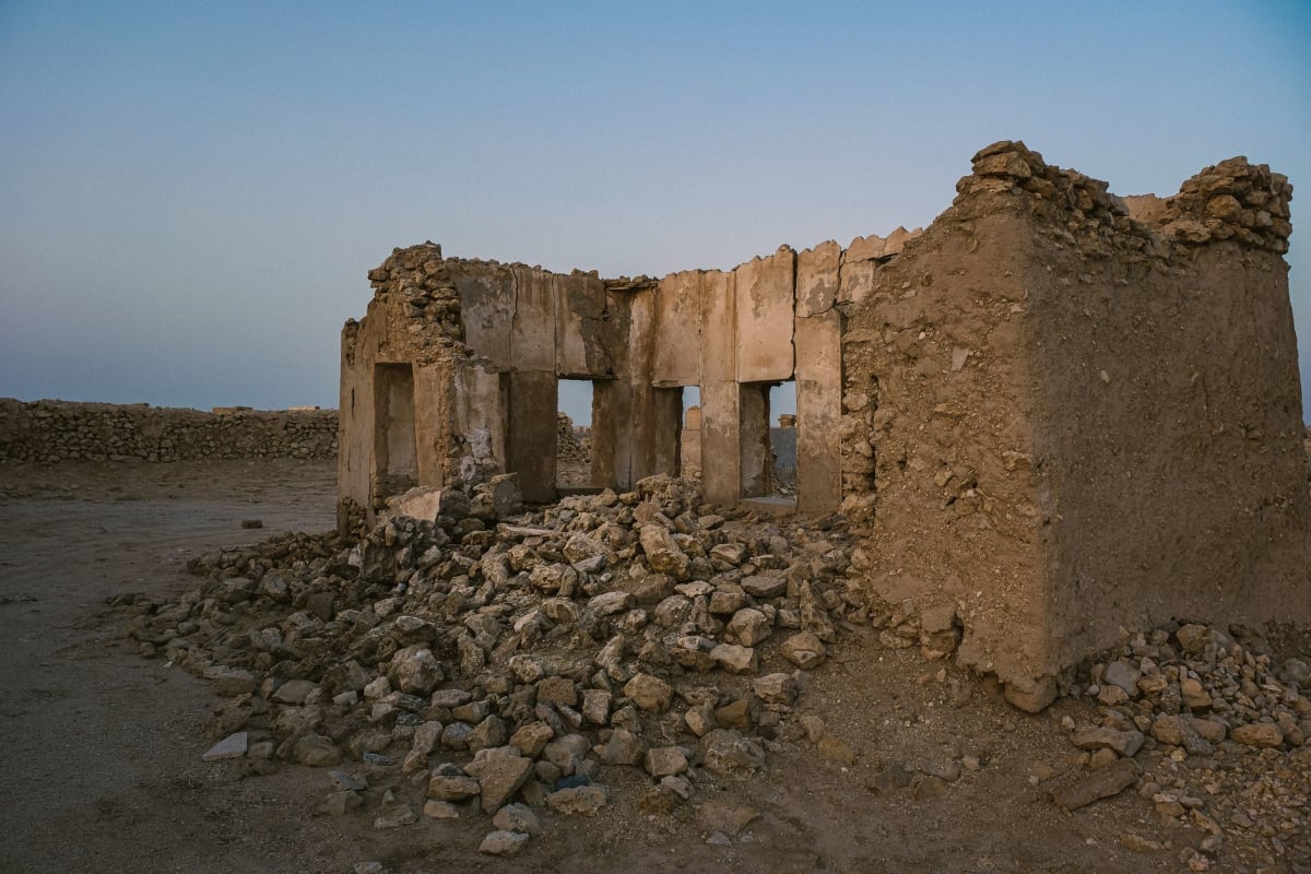 Filas de lápidas blancas en el Cementerio de Guerra de Tobruk, tierra roja y cielo despejado, el Mediterráneo visible al pie de la pendiente