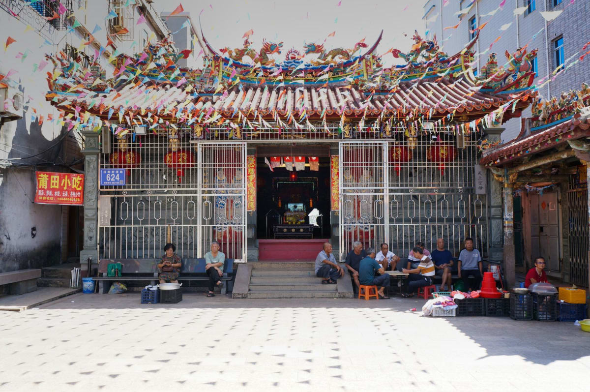 La cámara del altar principal del Templo de A-Ma, densa de humo de incienso, linternas rojas colgando del techo y ofrendas dispuestas ante la estatua dorada de Mazu