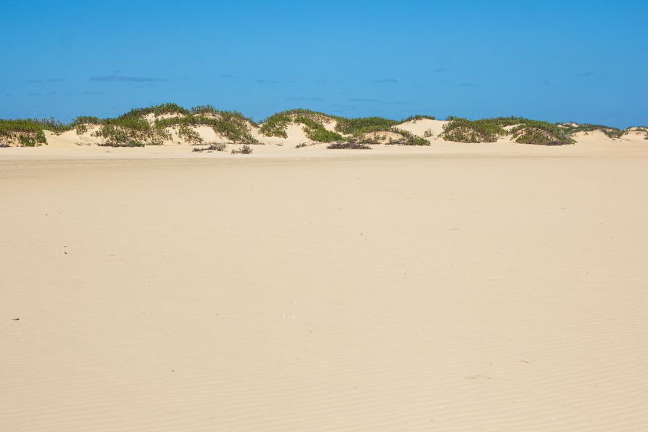 The pale sand dunes rising behind Anakao village at sunset, with the coastline and calm sea visible below