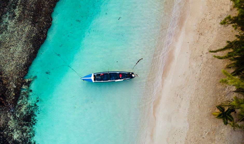 Un remero local guiando una estrecha piragua tallada de un tronco a través del canal en calma entre Sainte Marie e Ile aux Nattes