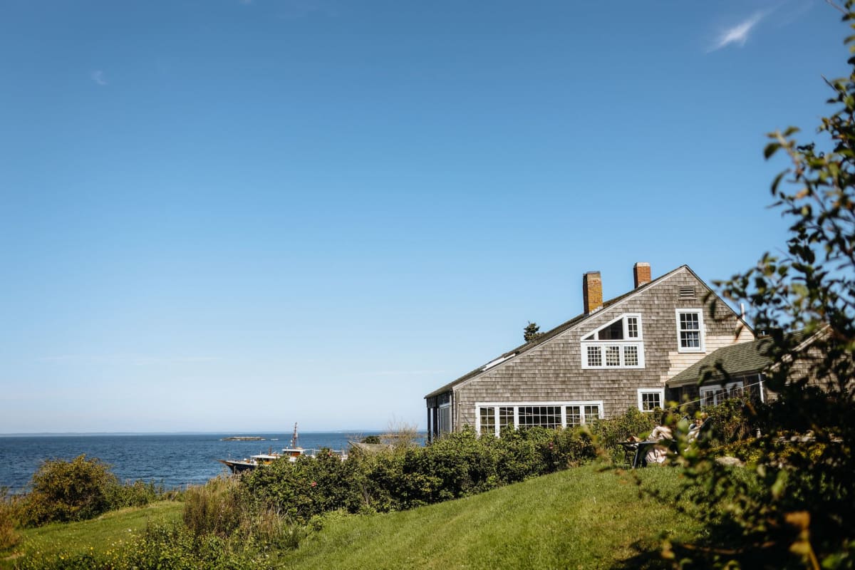El faro de la isla Monhegan y la cabaña del farero en el punto más alto de la isla, el mar visible en tres lados