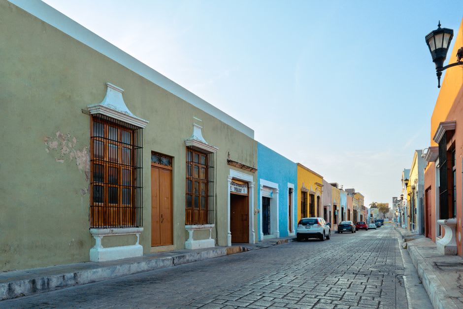 Calle residencial tranquila en Calkiní, Campeche, con casas bajas pintadas y sombras de la tarde