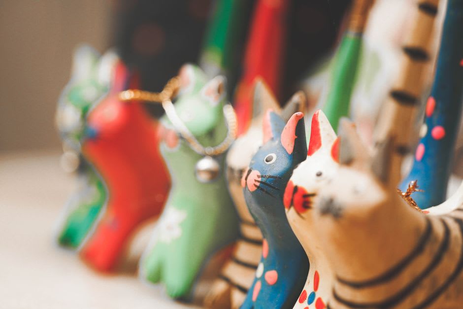 Une rangée de jouets en bois peints à Cofradía de Suchitlán — petits animaux aux pigments naturels vifs disposés sur une étagère d'atelier, plantations de café visibles par la porte ouverte à l'arrière-plan