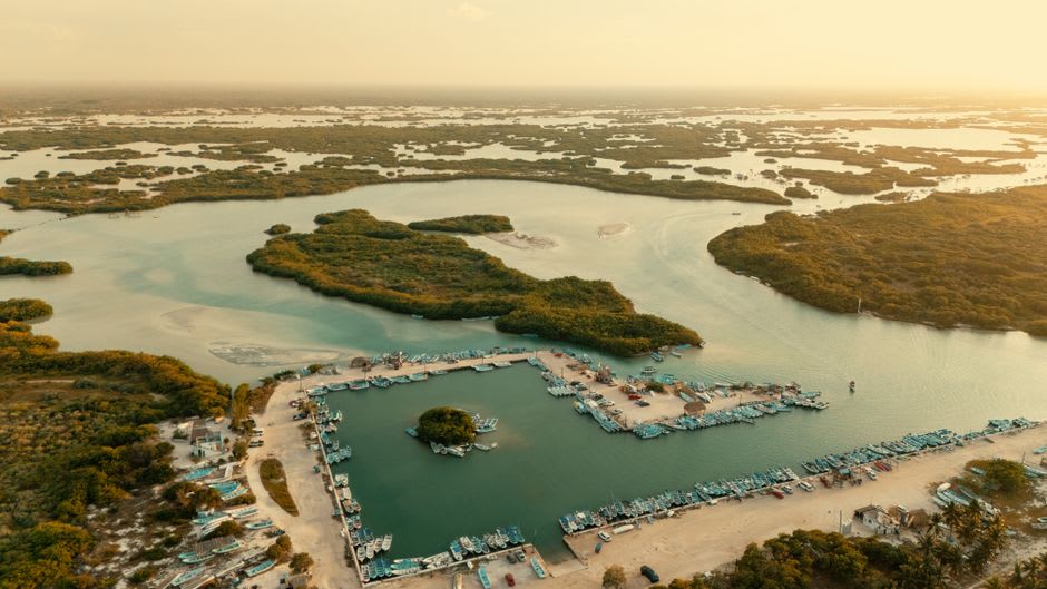 Place principale d'Escárcega au crépuscule, familles qui marchent et charrette de mangue éclairée par un parasol jaune au premier plan