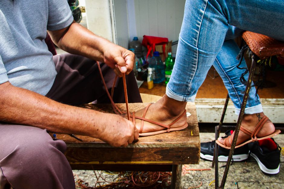 Huaraches de cuero secándose en un tendedero afuera de un taller de La Noria, correas trenzadas en tonos tierra y piel natural