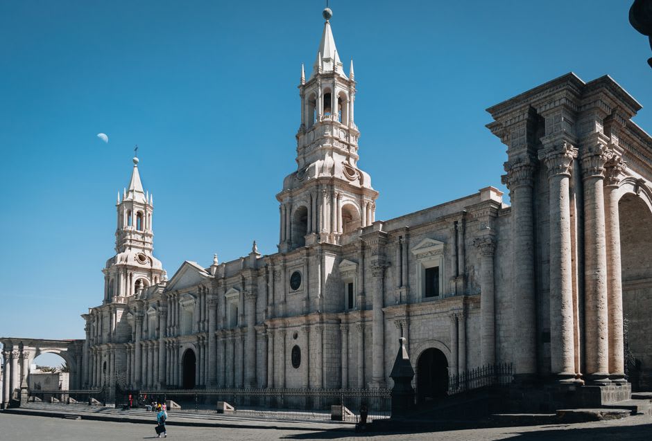 La arcada colonial y la plaza de Linares bajo un cielo azul despejado, con la catedral visible al fondo
