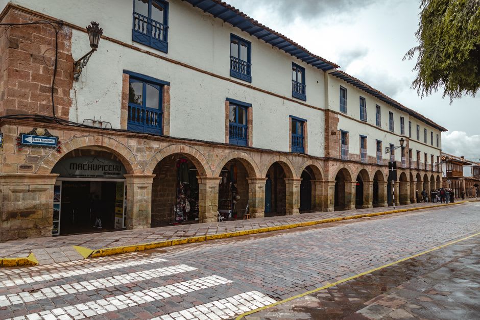 The colonial centro of Linares, a row of old arcaded commercial buildings along the main plaza with orange trees casting shade over the sidewalk in the morning light