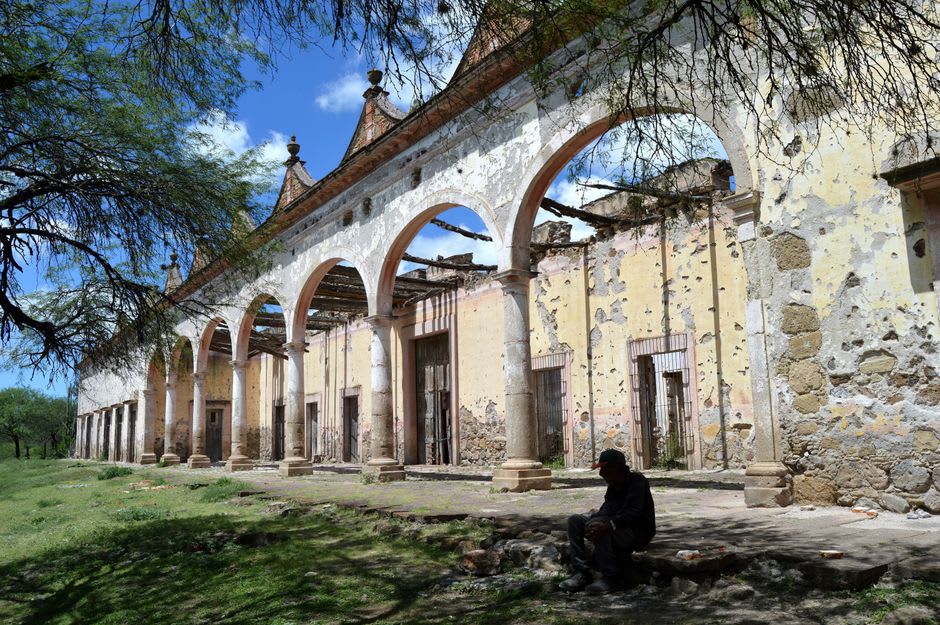 Una larga arcada de piedra de una vieja hacienda lechera afuera de Polotitlán, arcos desgastados extendiéndose por una llanura ganadera seca bajo un cielo amplio y pálido