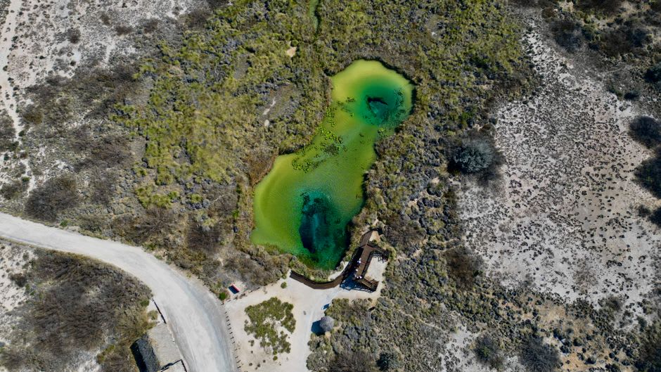 Un kayak sobre el agua quieta de un brazo de cañón inundado en Presa de la Amistad, paredes de cañón color ocre recibiendo la luz de última hora de la tarde en los lados mexicano y texano