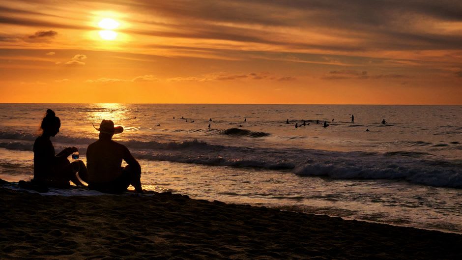 Lumière chaude de fin de journée tombant sur le front de mer de San Pancho, avec des barques de pêche tirées sur le sable