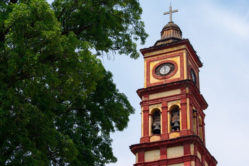 La torre del campanario de la parroquia de Sinaloa de Leyva elevándose sobre los portales coloniales en sombra de la plaza principal