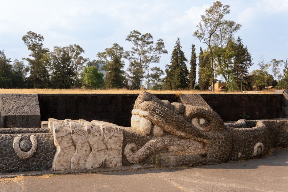 El muro de serpientes Coatepantli en Tula, sus paneles de piedra caliza labrada mostrando el motivo repetido de serpientes devorando cráneos en bandas continuas, la antigua frontera decorativa tolteca preservada en el lado norte de la plaza principal