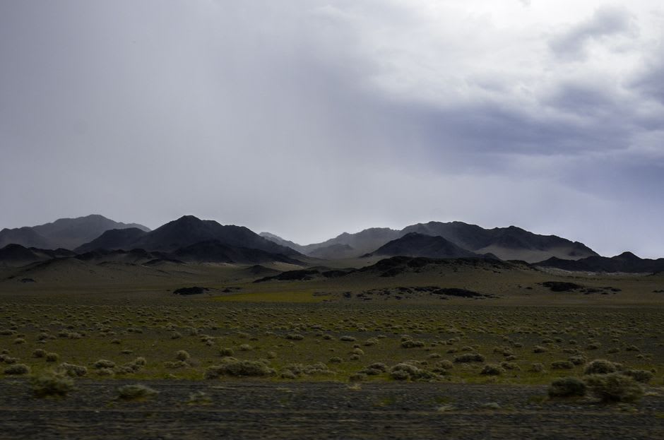 Larges rues poussiéreuses de Dalanzadgad avec des montagnes désertiques basses visibles à l'horizon