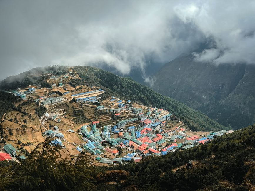 Prayer flags and stacked rooftops of Namche Bazaar seen from above