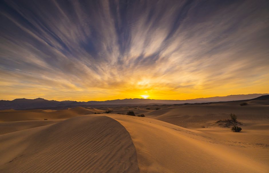 Crestas rocosas del Macizo de Termit al amanecer con dunas de arena en la base