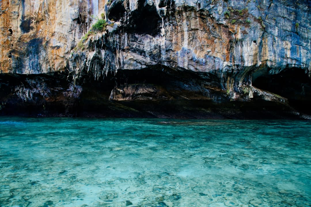 Sunlight filtering through coral cliffs onto the still water of Matapa Chasm