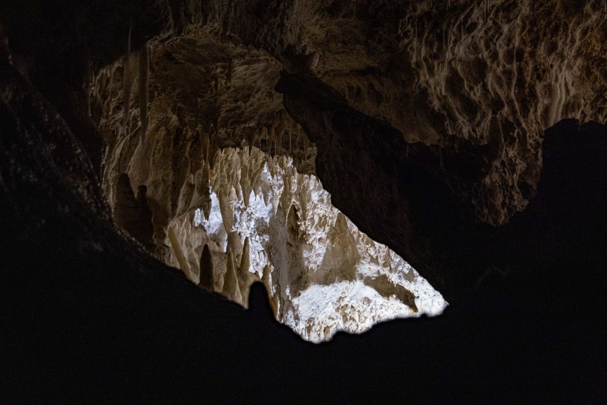 La piscine à l'intérieur de la Grotte de Palaha en surge avec la houle de l'océan, eau turquoise et blanche contre le calcaire sombre