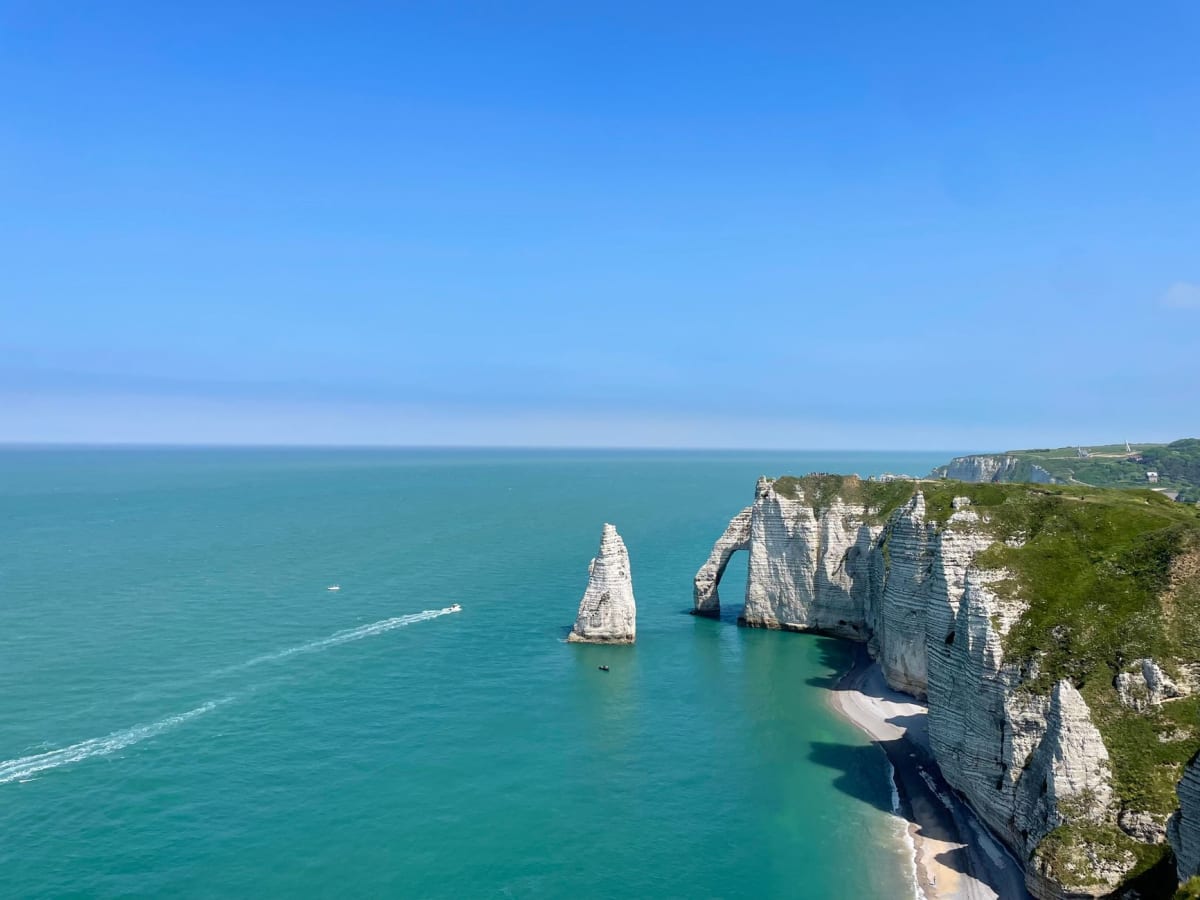 Guijarros mojados por la lluvia en la playa de Étretat con los acantilados de tiza desapareciendo entre la niebla baja