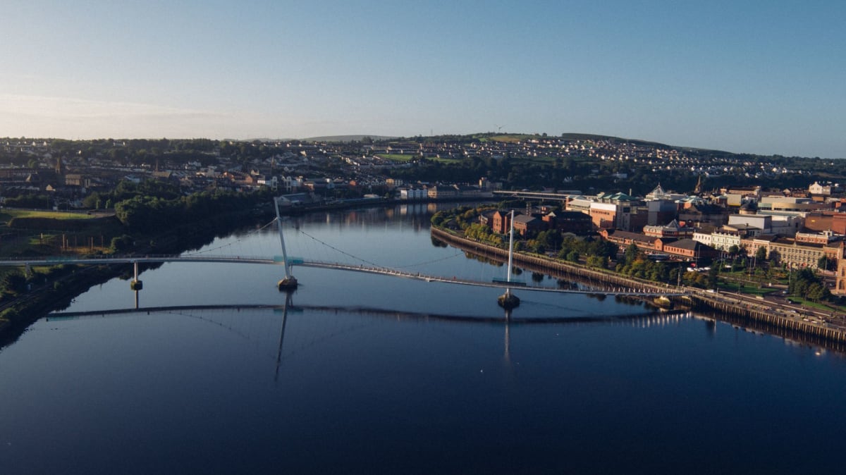 El Ayuntamiento de Derry del siglo XIX reflejado en el agua quieta del río Foyle durante la marea baja, piedra y cristal