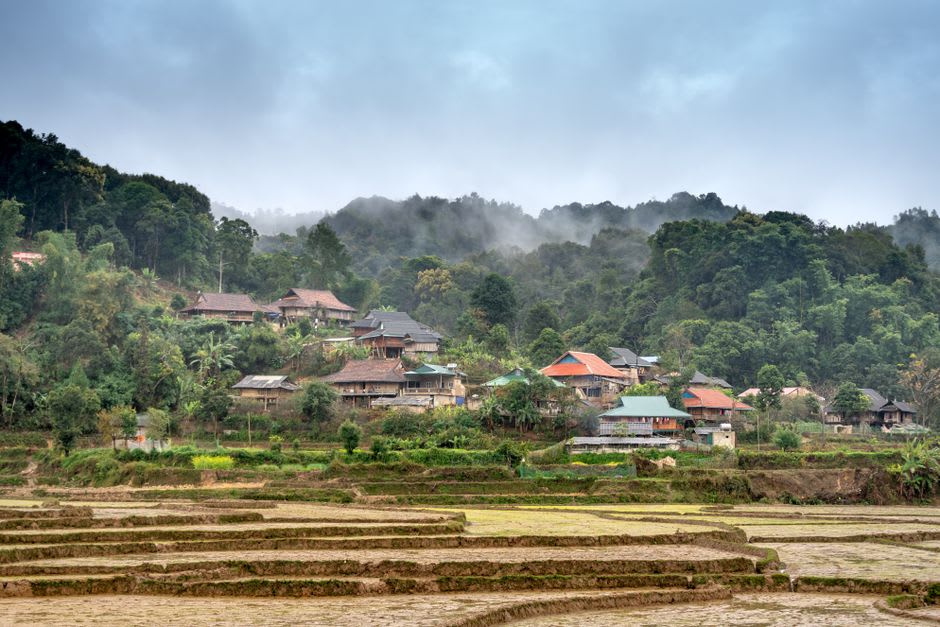 Una casa de una aldea de tribu de montaña en Nor Lae con terrazas montañosas visibles detrás