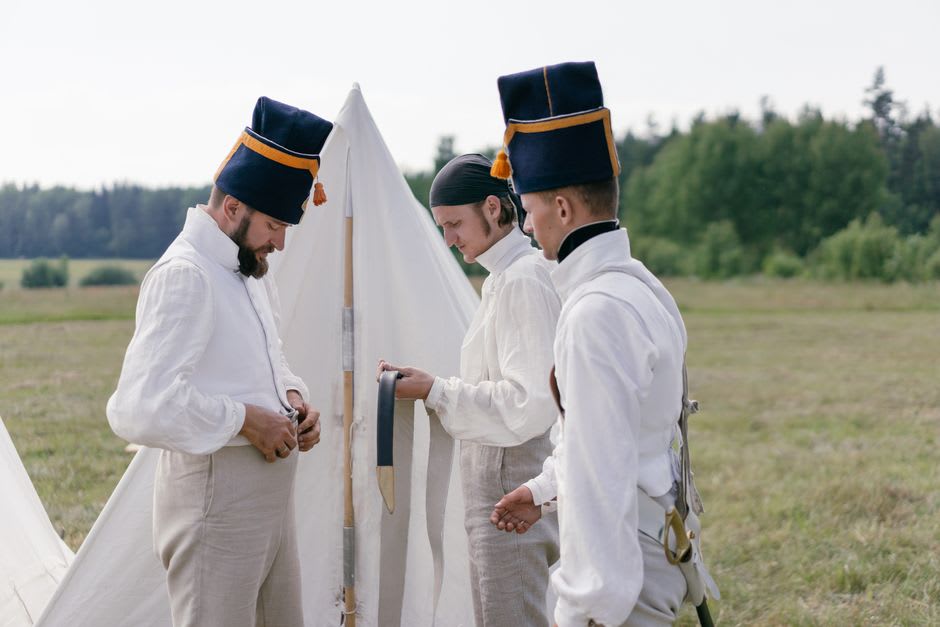 Costumed interpreter in 18th-century French military uniform standing at the fortress gate