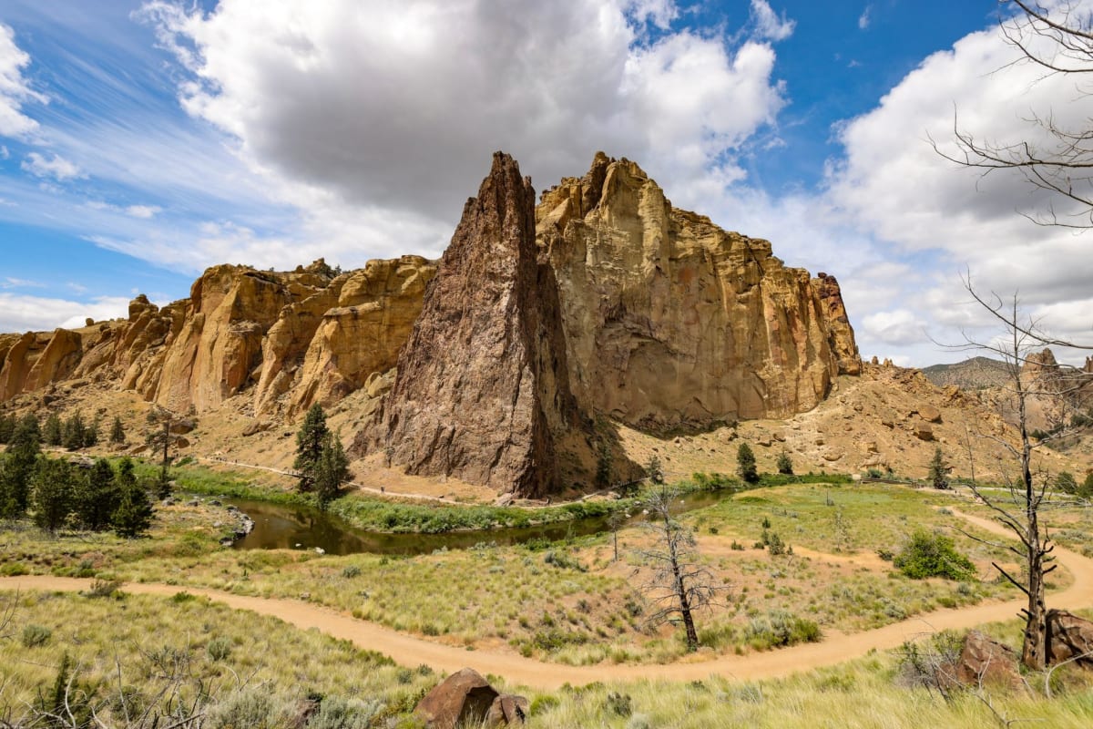 La rivière Crooked s'incurvant à la base des falaises de tuf doré à Smith Rock avec de l'armoise le long des berges