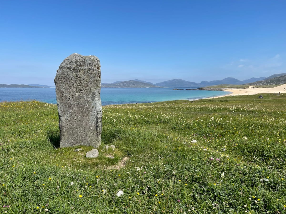 El círculo principal de Callanish, piedras oscuras contra un cielo vespertino pálido, con el lago brillando detrás