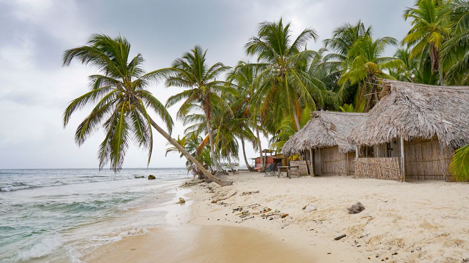 A tiny San Blas islet with a handful of palm trees and a thatched hut, surrounded by turquoise water