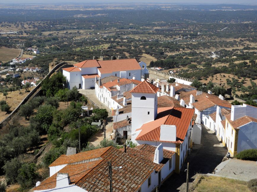 Whitewashed village lane in Alvor climbing toward the hilltop Igreja Matriz church with its carved Manueline doorway