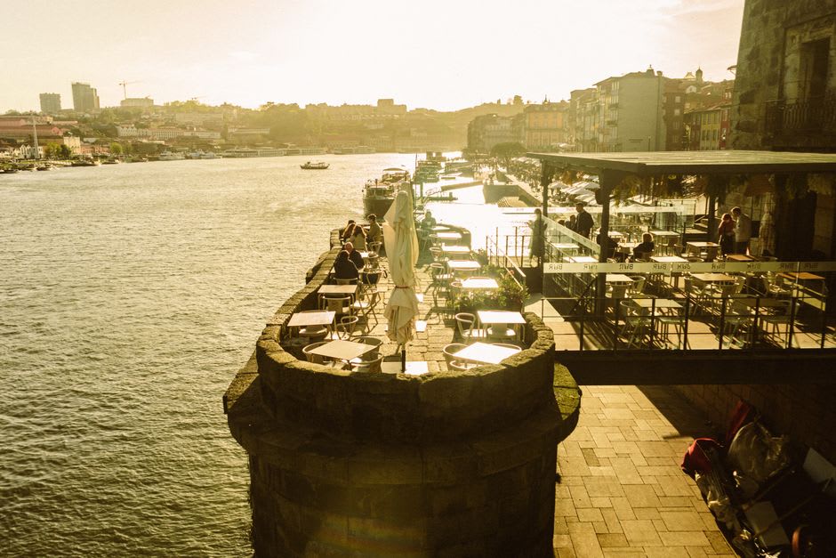 Riverside café tables along the Tâmega in Amarante at golden hour with the arched stone bridge in view