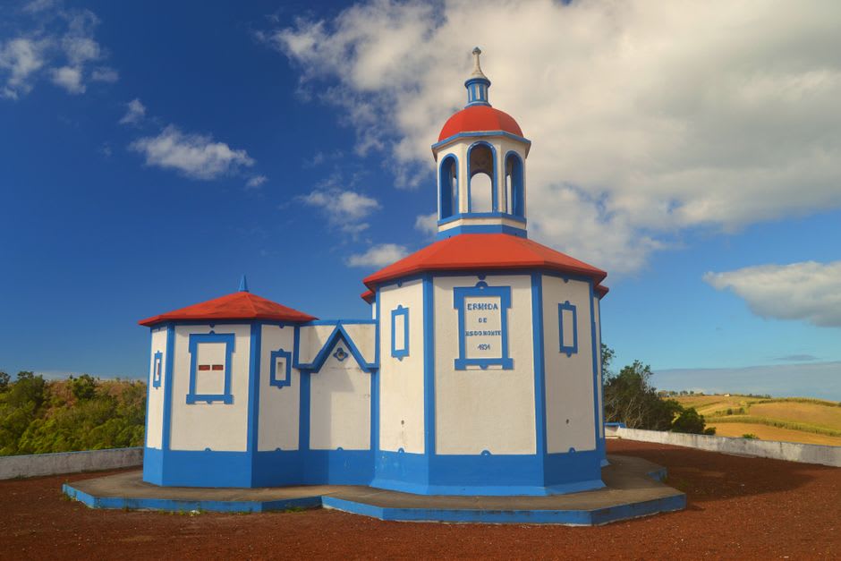 Small brightly painted Império chapel decorated with flags and paper garlands during a Holy Spirit festival in Angra do Heroismo