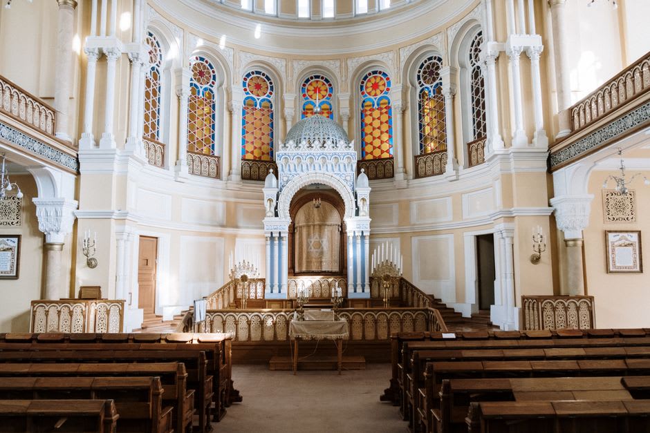 Interior de la sinagoga Bet Eliahu en Belmonte con sencillos bancos de madera y ventanas con la Estrella de David