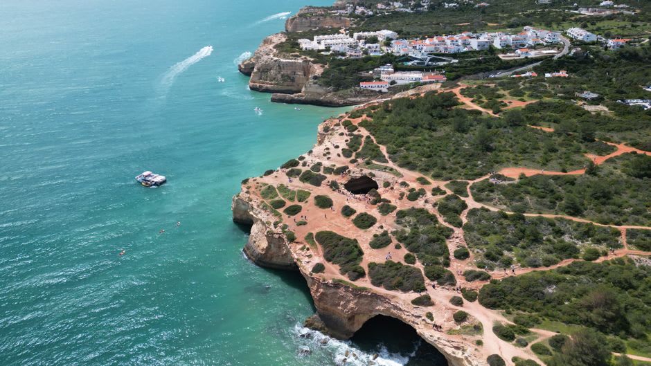 Barco acercándose a la abertura abovedada de la cueva marina de Benagil, con la luz del sol cayendo sobre la playa escondida en su interior