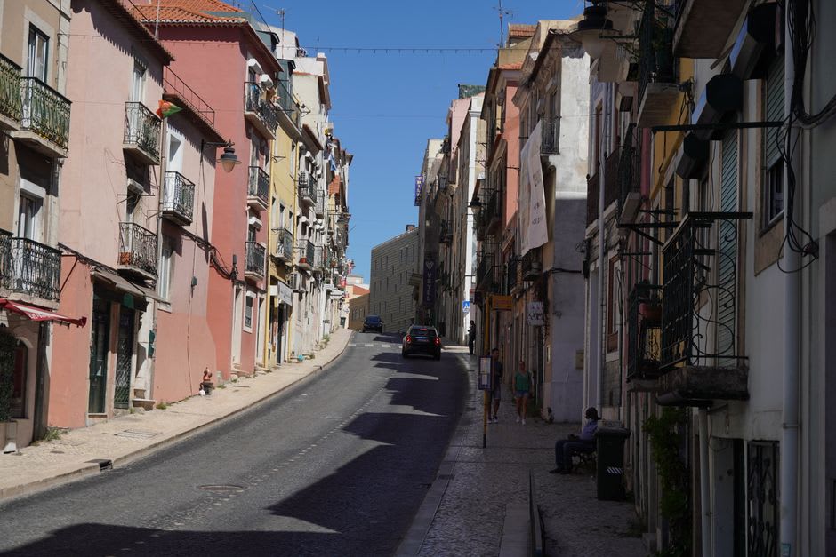 Steep cobbled street in Covilhã lined with old wool-mill buildings and mountain views beyond