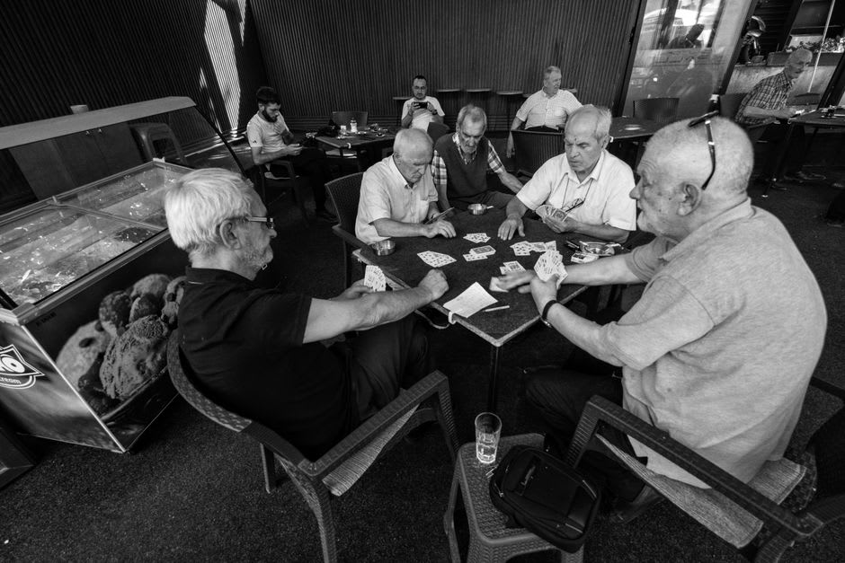 Elderly locals playing cards outside a café in Ericeira's Praça da República at sunset