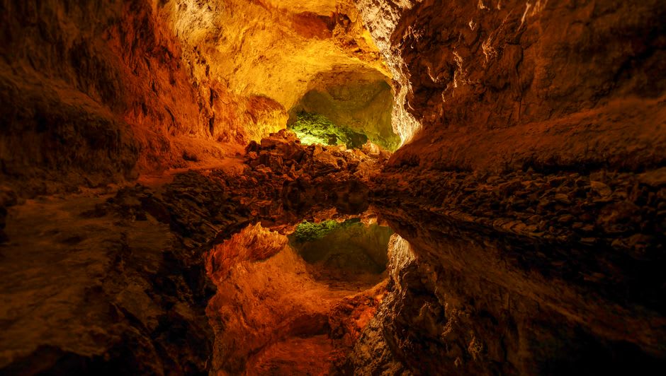 Underground volcanic lake inside Furna do Enxofre cave lit by a shaft of daylight from above