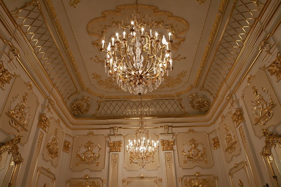 A gilded throne room inside Mafra Palace with marble floors and elaborate ceiling frescoes