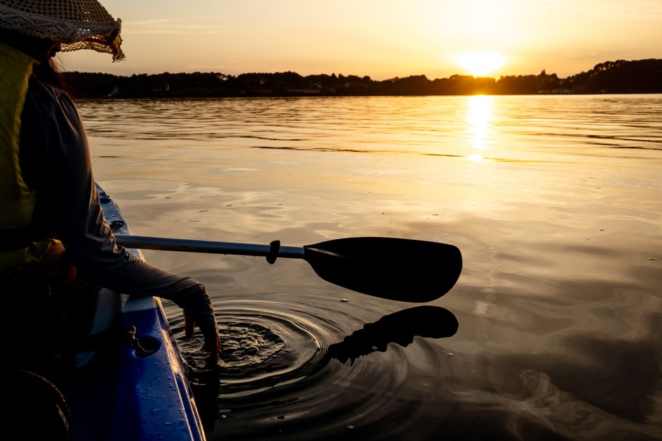 Kayaker paddling across the still water of the Lagoa de Melides lagoon at sunset