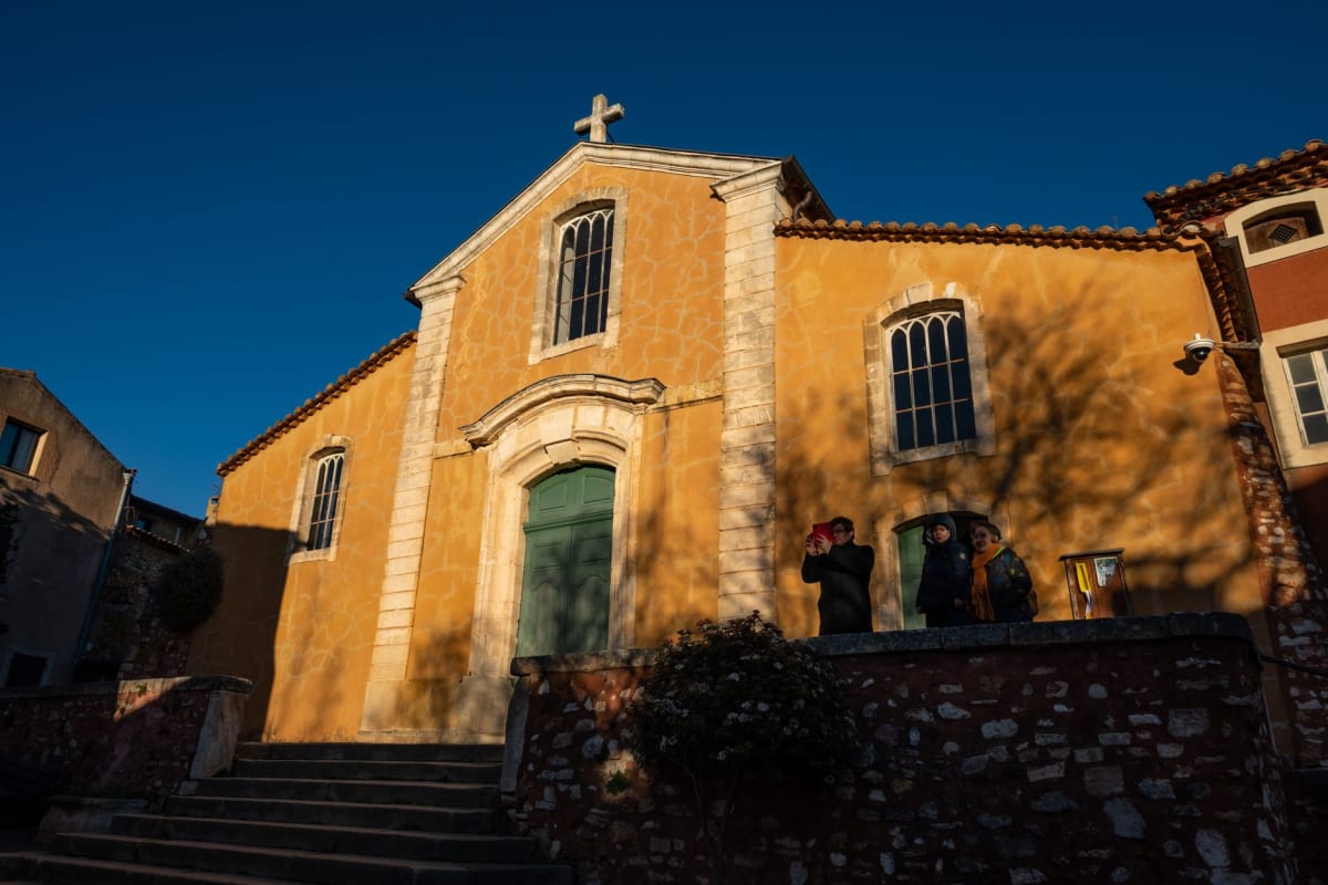 Roussillon's church tower turning gold-orange in the setting sun, the Luberon hills rolling blue in the distance