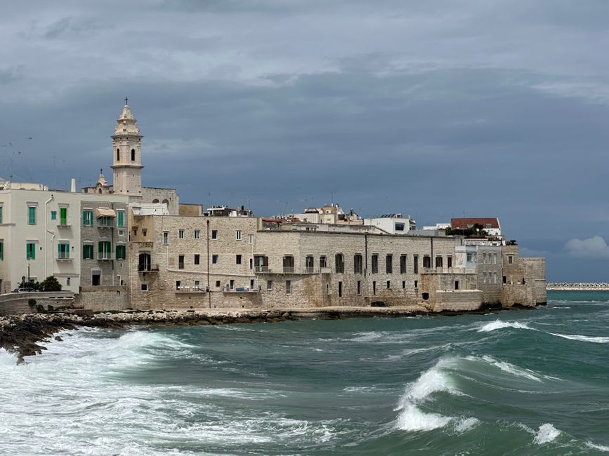 The twin-towered facade of Molfetta's Duomo Vecchio rising above the fishing harbour, boats moored below