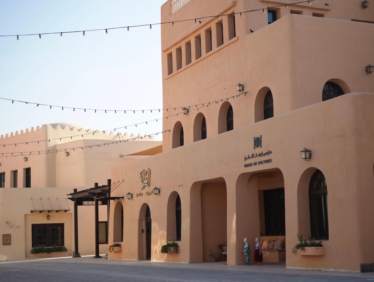 Wind-tower houses along the Al Wakrah waterfront with their slatted badgir towers casting grid-shadows on whitewashed walls