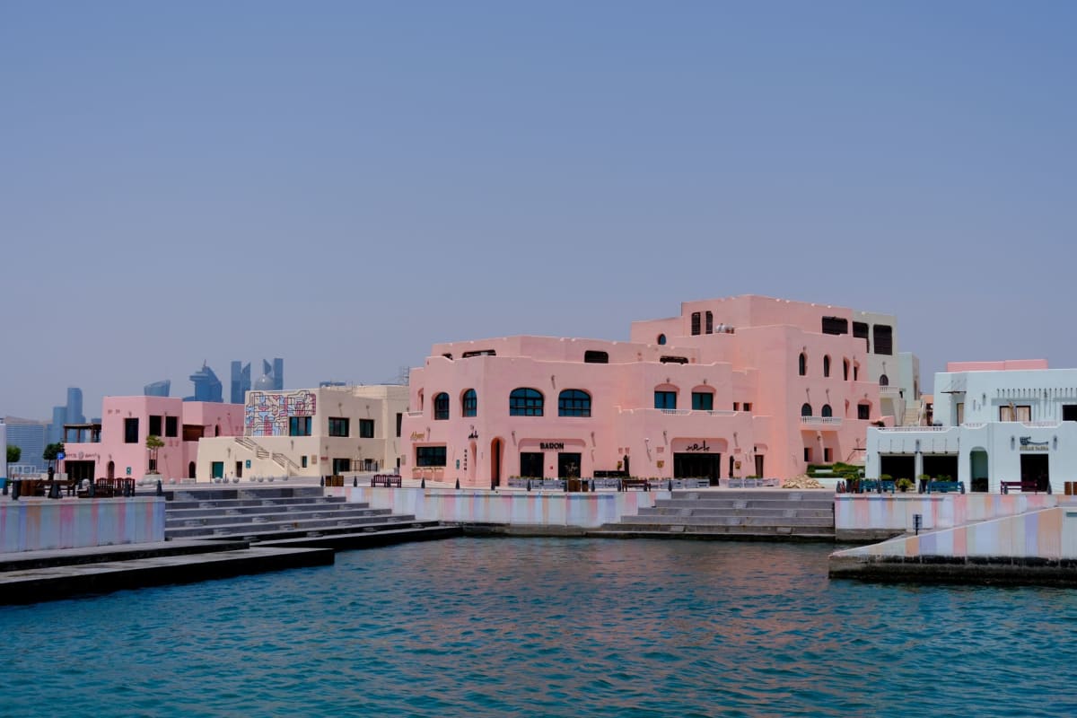 La marina de Porto Arabia à The Pearl avec des yachts reflétés dans l'eau calme du soir et des terrasses de cafés au-dessus du quai