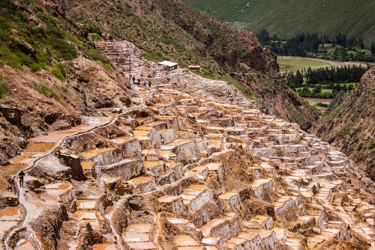 Bolsas de sal rosa de Maras en venta a la entrada del sitio, las terrazas continuando ladera arriba detrás del puesto