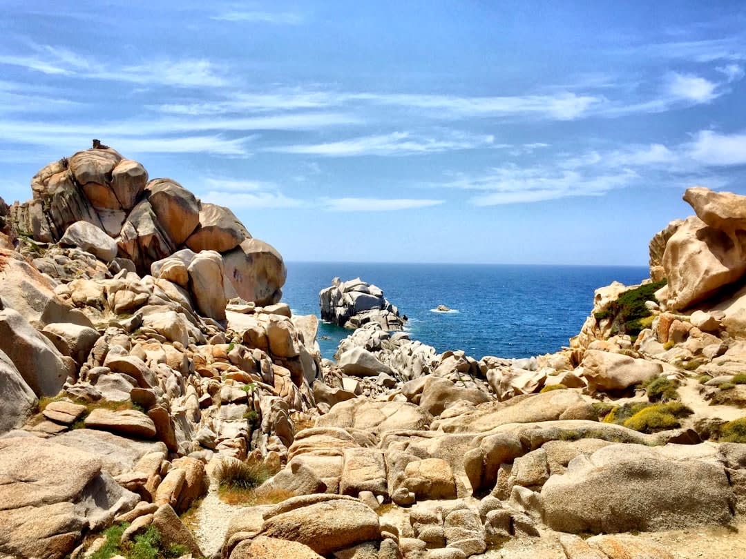 La arena pálida y las aguas transparentes y turquesas de la playa de Rena Bianca con la antigua torre de vigilancia en un extremo