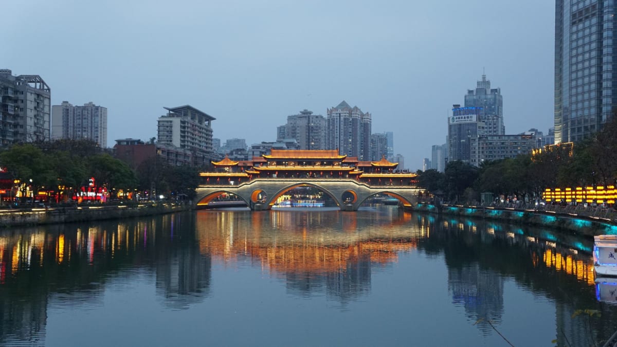 Une cour de maison de thé de Chengdu au parc Renmin, des chaises de bambou bondées de gens du coin buvant du thé au jasmin dans la lumière de l'après-midi