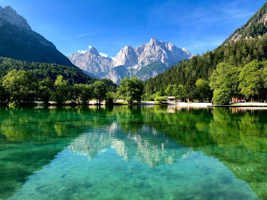 The bronze ibex statues at the edge of Lake Jasna with turquoise water and forested slopes behind