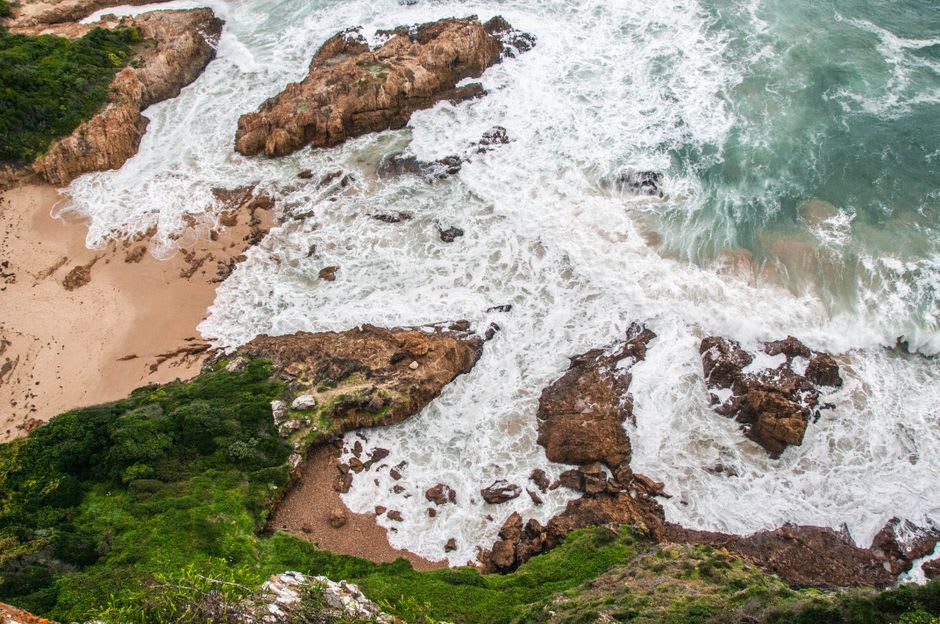 Costa escarpada de Sudáfrica con olas rompientes y colinas verdes a lo largo de la Costa Salvaje